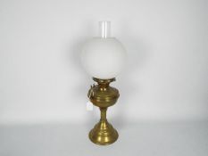 A brass oil lamp with fluted column support and spherical glass shade, approximately 48 cm (h).