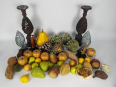 A collection of faux fruit, candle holders / stands and similar.