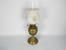 A brass oil lamp with floral decorated shade,