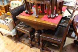 Oak draw leaf dining table on carved twin supports, with four studded leather chairs.