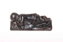 Cast metal reclining child figure, 11.5cm across.