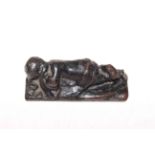 Cast metal reclining child figure, 11.5cm across.