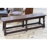 Rectangular oak jointed bench stool on turned supports and stretchers, 28cm by 142cm by 48cm.