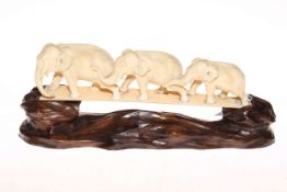 Japanese ivory Okimono of chain of graduated elephants, 24cm across, with carved wood stand.