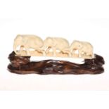 Japanese ivory Okimono of chain of graduated elephants, 24cm across, with carved wood stand.