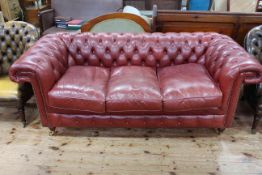 Deep buttoned red leather three seat Chesterfield settee, 200cm wide.