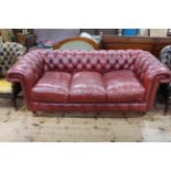 Deep buttoned red leather three seat Chesterfield settee, 200cm wide.