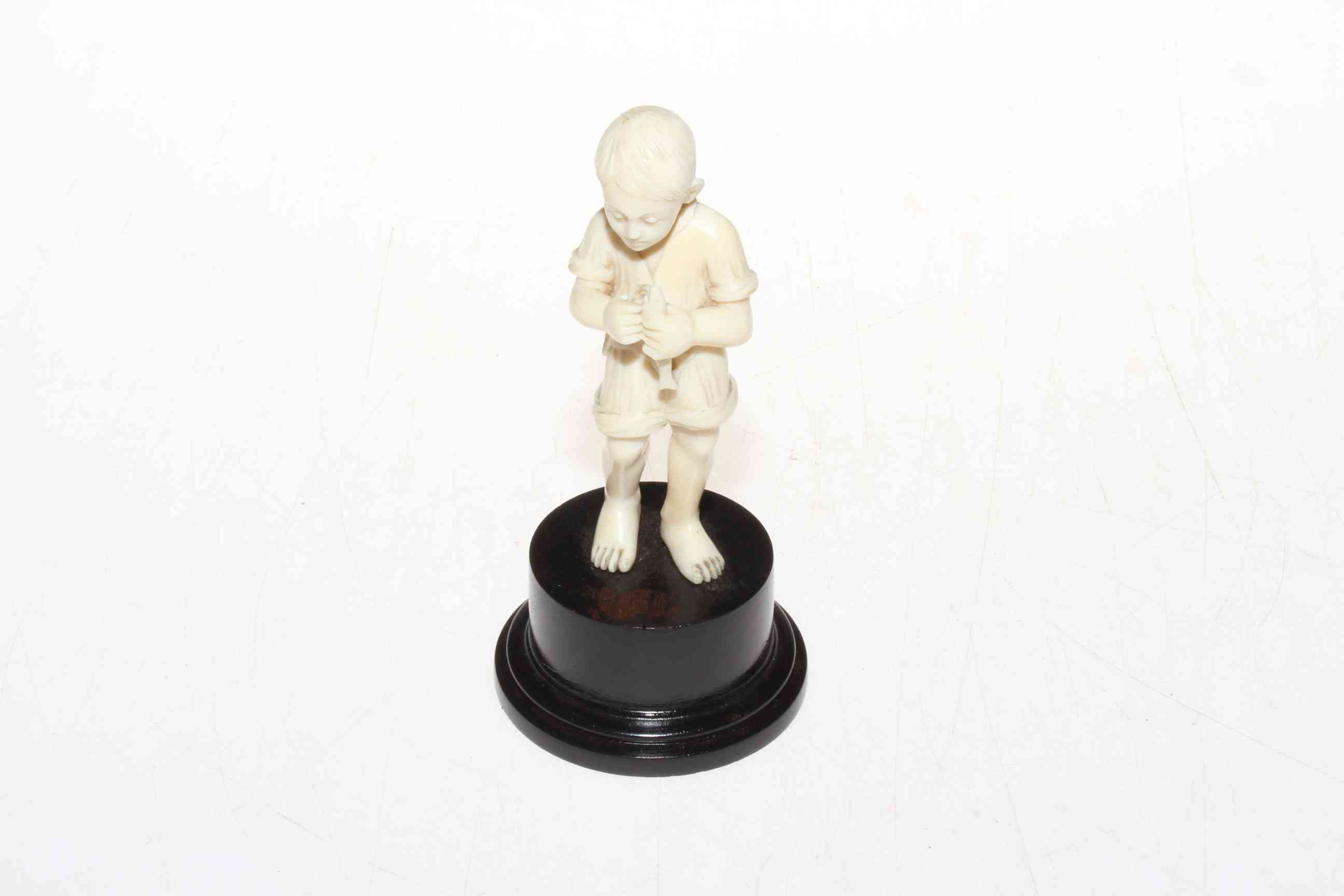 1920's well carved ivory figure of young boy with fish, on plinth base, 13cm.