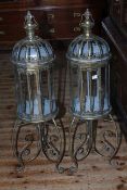 Pair of gilt metal and glazed hall lanterns on ornate stands, 109cm high.