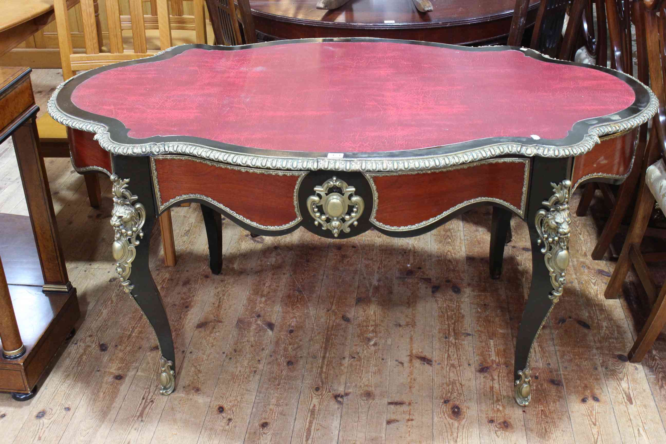 French ebonised and gilt metal mounted bureau plat, of oval shape with inset red leather,