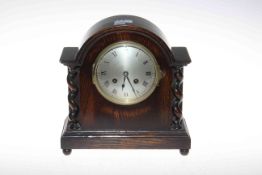 Small oak arch top mantel clock with twin barley twist columns and silvered dial.