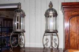 Pair of gilt metal and glazed hall lanterns on ornate stands, 109cm high.