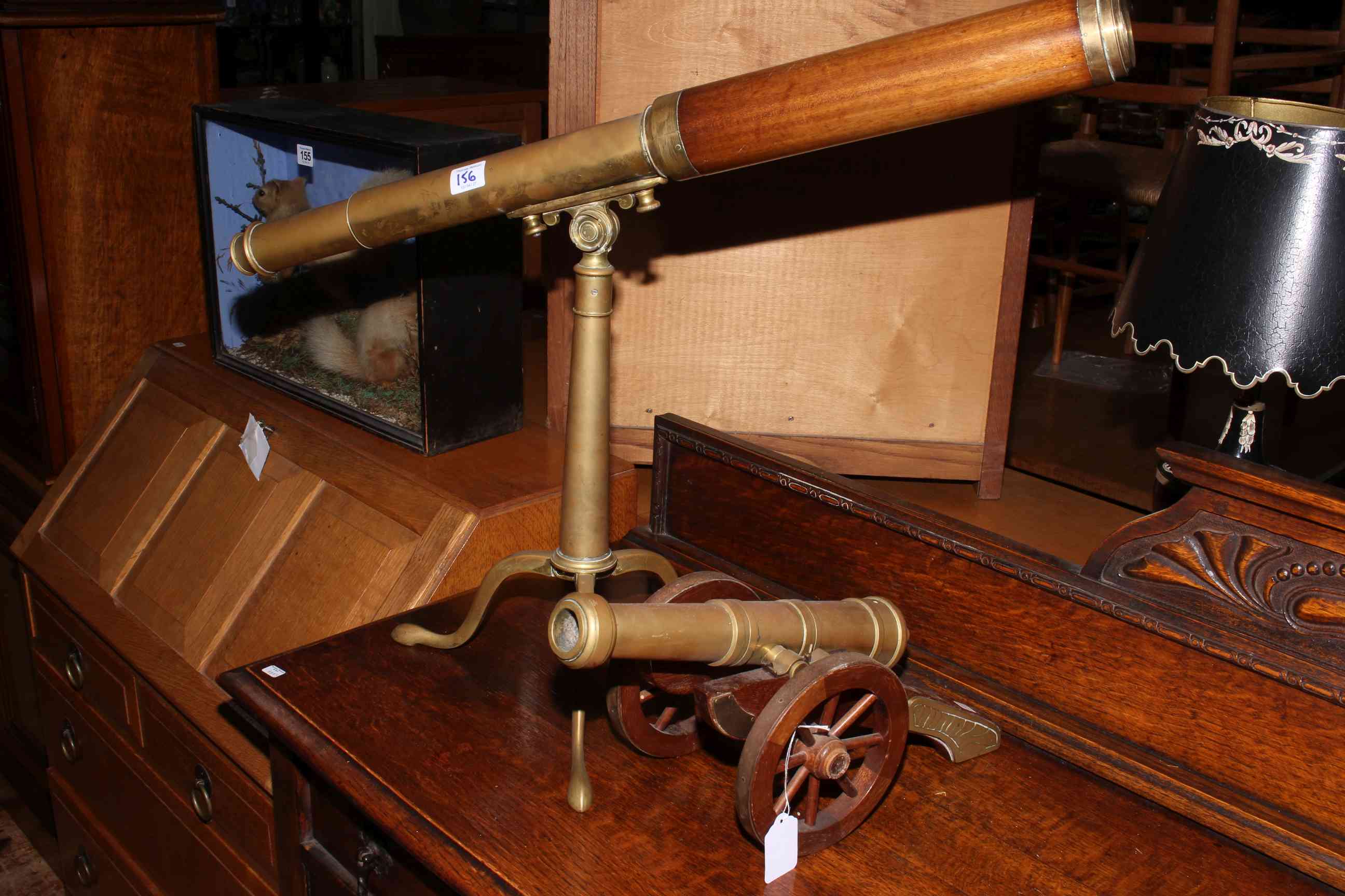 Brass and mahogany telescope on tripod base and brass and mahogany table top model of a canon.