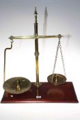 Brass balance scales and weights mounted on wooden stand. 51cm by 58cm.