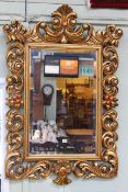 Ornate gilt framed bevelled wall mirror, 125cm by 84cm overall.