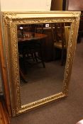 Gold coloured swept framed wall mirror, 105cm by 76cm overall.