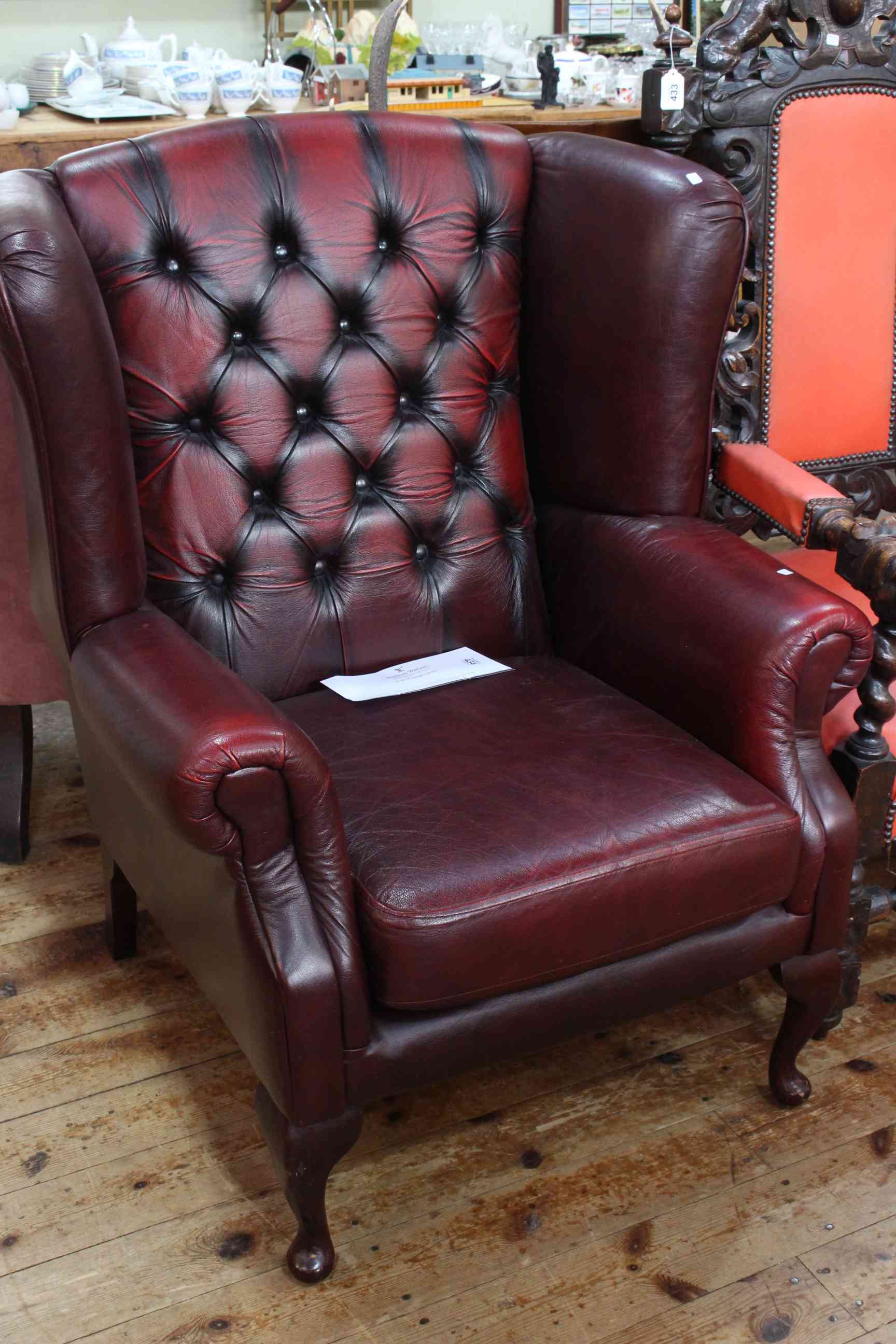 Ox blood buttoned back wing armchair on cabriole legs.