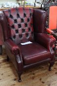 Ox blood buttoned back wing armchair on cabriole legs.