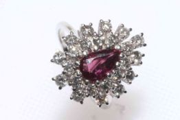 Ruby and diamond cluster ring set in 18 carat white gold having drop shaped ruby within ornate