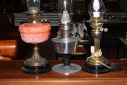 Three oil lamps including porcelain peach reservoir and a brass columned oil lamp.