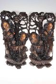 Two Oriental ebonised carved wood statues depicting folk pouring tea, 47cm high.