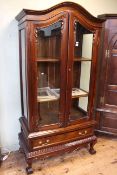 Arched top vitrine having two glazed doors above a long drawer on claw feet,