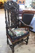 Heavily carved Jacobean style elbow chair with blue floral needlework seat.