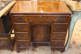 Walnut kneehole desk having long drawer above central cupboard door flanked by two banks of three