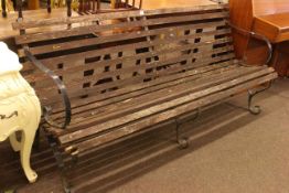 Weathered wrought iron scroll arm and wood slat garden bench, 181cm long.