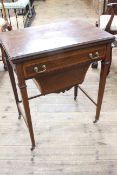 Edwardian inlaid mahogany swivel top games/sewing table having frieze drawer above deep sewing