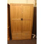 Contemporary light oak wardrobe having two doors above four drawers.