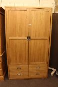 Contemporary light oak wardrobe having two doors above four drawers.