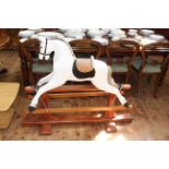 White painted rocking horse on stained wood safety stand, 105cm high by 134cm long.