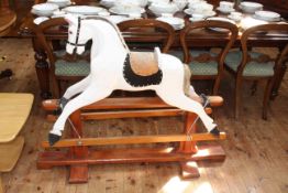 White painted rocking horse on stained wood safety stand, 105cm high by 134cm long.