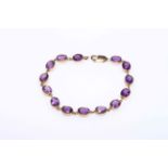 Amethyst and 9 carat gold bracelet having fourteen oval stones, 19cm length.