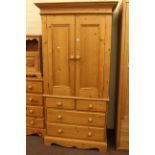 Pine combination wardrobe having two doors above two short and two long drawers.