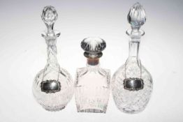 Silver mounted crystal decanter and two further decanters with silver labels.