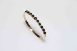 Sapphire and diamond 14k gold bangle, set with ten sapphires divided by pairs of brilliants.