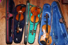 Three 3/4 size cased violins and bows.