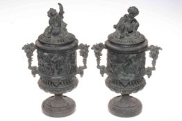 Pair of decorated cart iron cherub urns, 35cm high.