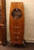 Contemporary rocket shaped cabinet having circular glazed panel door above three drawers,