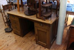 Edwardian oak pedestal desk having five drawers and panelled door cupboard,