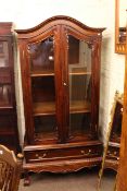 Hardwood arched top vitrine having two glazed panel doors above a drawer on ball and claw legs,