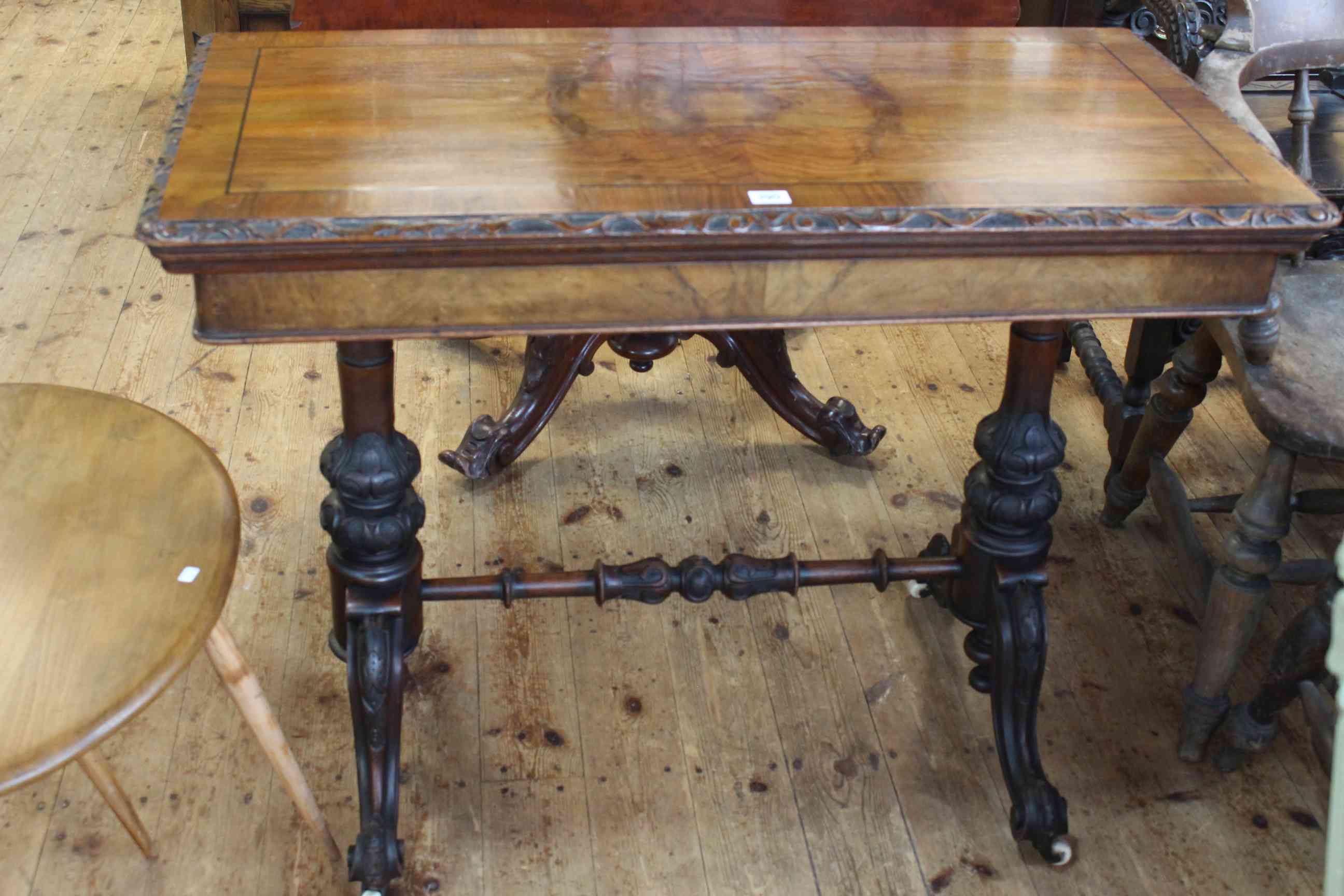 Victorian walnut fold top card table raised on turned carved pillars to four scrolled legs joined