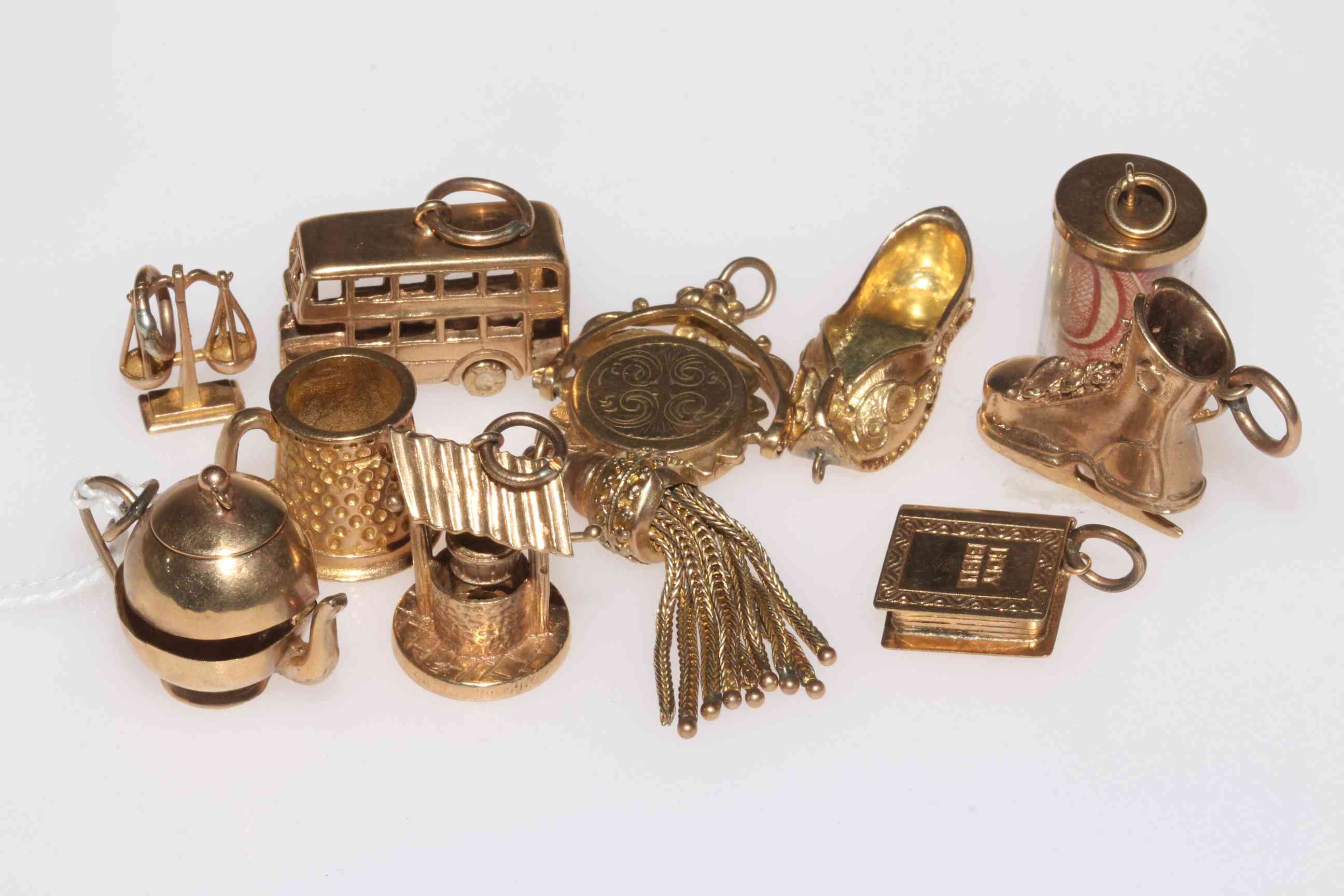 Collection of eleven 9 carat gold charms including ice skate and London bus.