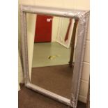 Swept chromed framed bevelled wall mirror, 107cm by 76cm overall.