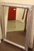 Swept chromed framed bevelled wall mirror, 107cm by 76cm overall.