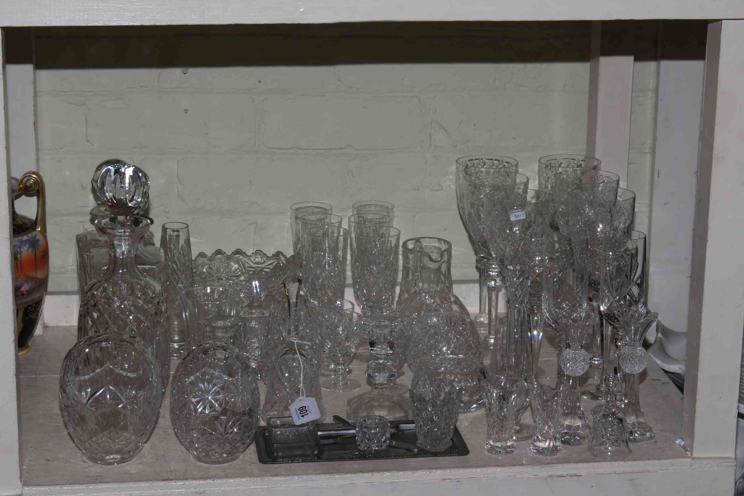 Three crystal glass decanters and various glassware.