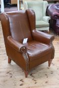 Tan leather and studded wing armchair.