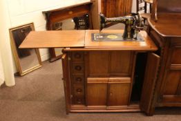 Vintage Singer cabinet sewing machine fitted with drawers containing sewing accessories.